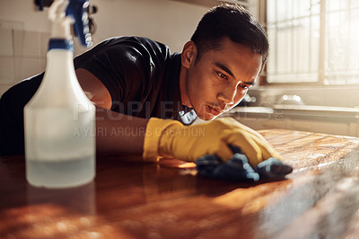 Buy stock photo Shot of a young man disinfecting a kitchen counter at home