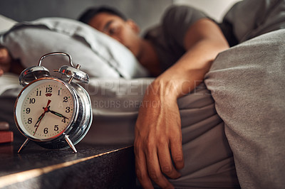 Buy stock photo Alarm clock, relax and man sleeping in the bed of his modern apartment in the morning. Lazy, resting and closeup of a timer bell with a male person taking a nap and dreaming in bedroom at his home.
