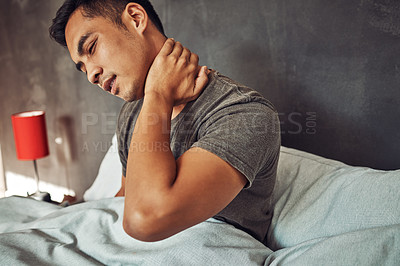 Buy stock photo Shot of a young man experiencing neck pain after waking up in bed at home