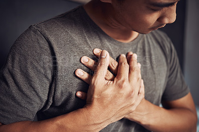 Buy stock photo Shot of a young man experiencing chest pain at home
