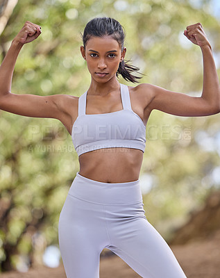 Buy stock photo Portrait of a sporty young woman flexing her biceps outdoors