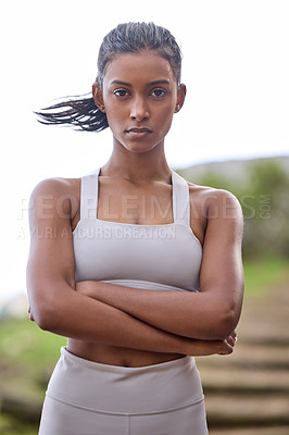 Buy stock photo Portrait of a sporty young woman standing with her arms crossed outdoors