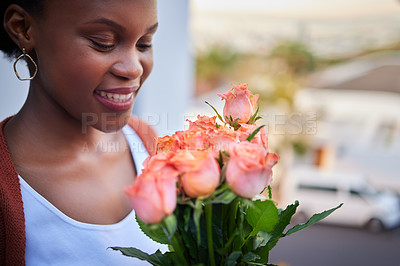 Buy stock photo Shot of an attractive young woman standing alone at home and holding a bouquet of roses