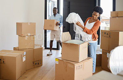 Buy stock photo Shot of a young couple packing their belongings at home