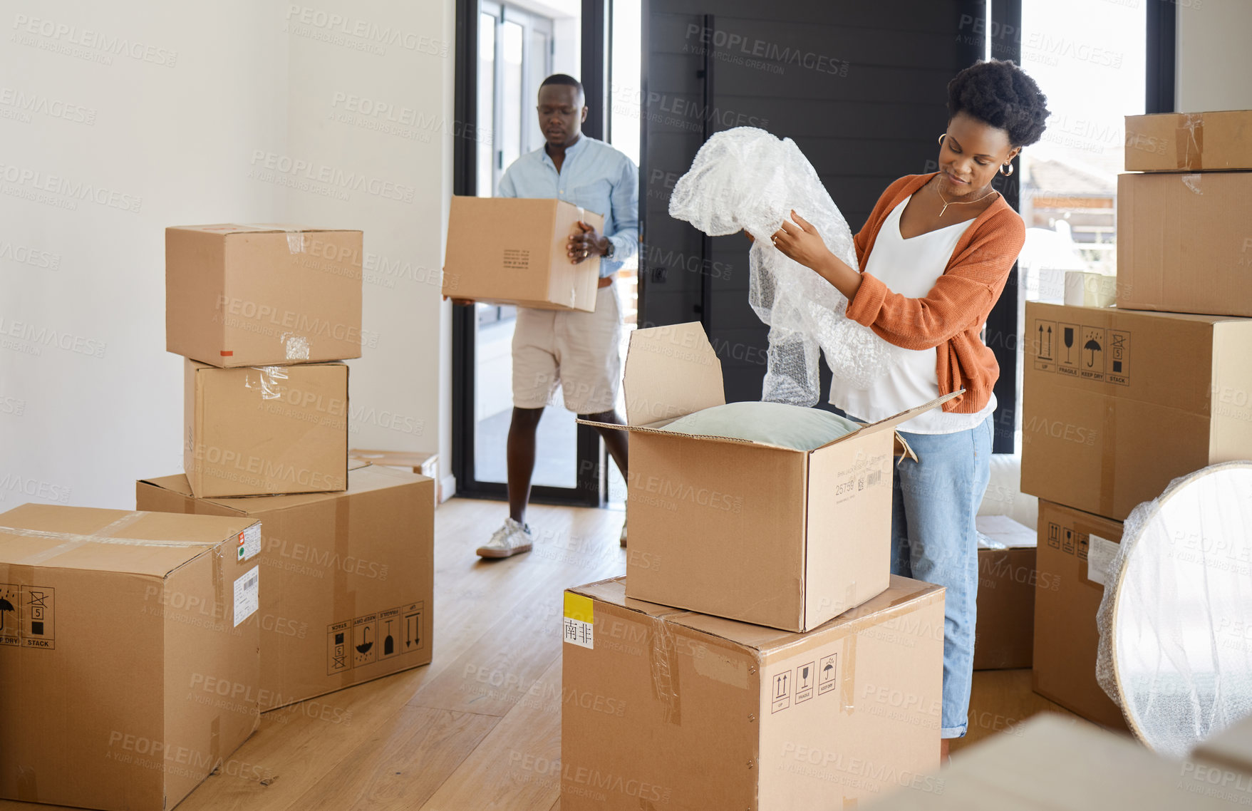 Buy stock photo Shot of a young couple packing their belongings at home