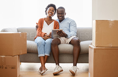 Buy stock photo Couple, new home and tablet with boxes, couch and lounge for moving or relocation in living room. African woman and man on tech as happy in packing for apartment, house or property as married people