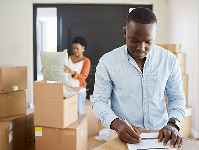 Buy stock photo African, couple and boxes on checklist in apartment for moving, house and relocation on couch in living room. Woman, man and paper for plan in packing for future, new home or property as young people