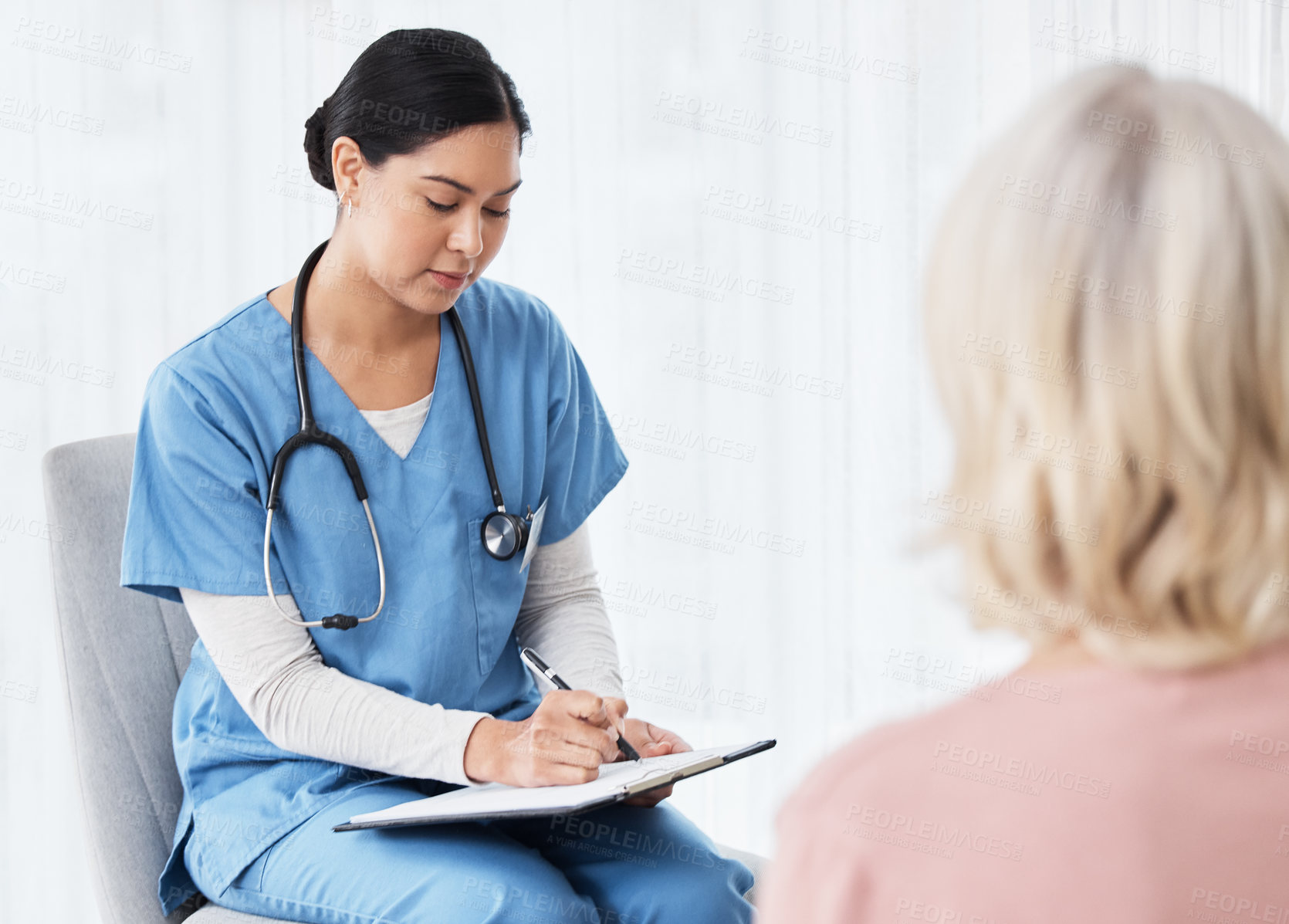 Buy stock photo Shot of a female nurse sitting with a clipboard while having a consultation with a patient