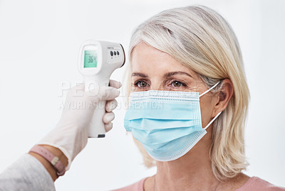 Buy stock photo Shot of a woman wearing a mask while having a temperature taken
