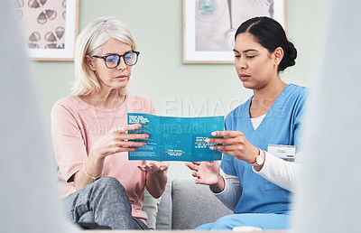 Buy stock photo Shot of a female nurse reading through a Covid-19 pamphlet