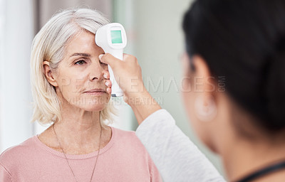 Buy stock photo Shot of a senior woman having her temperature taken