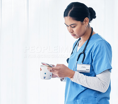 Buy stock photo Shot of a female nurse holding a cup of coffee while using her cellphone