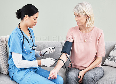 Buy stock photo Shot of a female nurse checking her patient's blood pressure