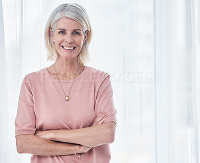 Buy stock photo Shot of a senior woman standing with her arms crossed while smiling at the camera