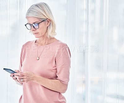 Buy stock photo Shot of a senior woman using her cellphone at home