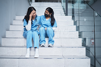 Buy stock photo Shot of a female nurse comforting her colleague while sitting on a staircase at work