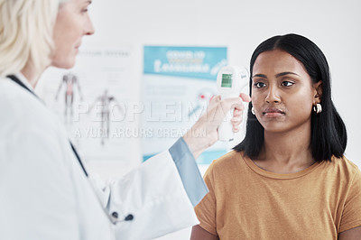 Buy stock photo Shot of a doctor examining a woman with a thermometer