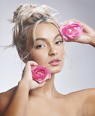 Buy stock photo Shot of an attractive young woman standing alone against a grey background and posing with flowers