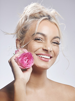 Buy stock photo Shot of an attractive young woman standing alone against a grey background and posing with a flower