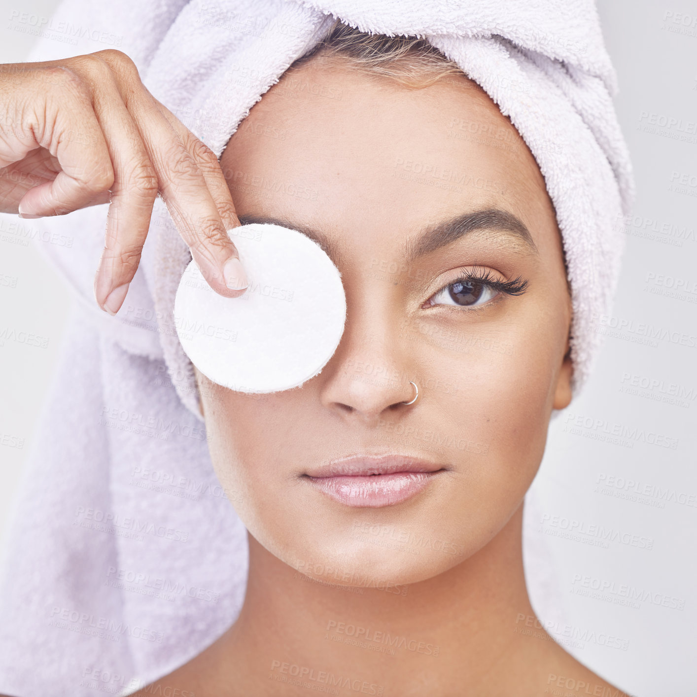 Buy stock photo Studio shot of a beautiful young woman applying products to her face using a cotton disc against a grey background