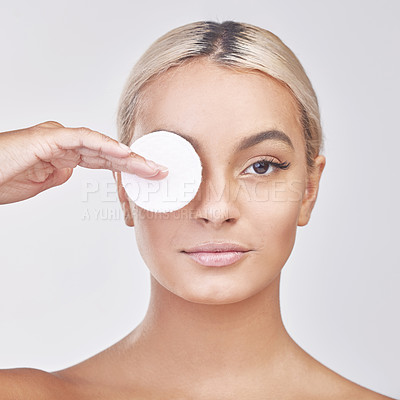 Buy stock photo Studio shot of a beautiful young woman applying products to her face using a cotton disc against a grey background