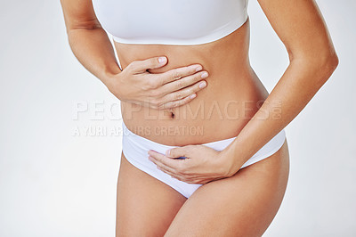 Buy stock photo Shot of a woman bent over with period cramps against a studio background