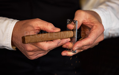 Buy stock photo Shot of an unrecognizable man using a clipper to cut a cigar