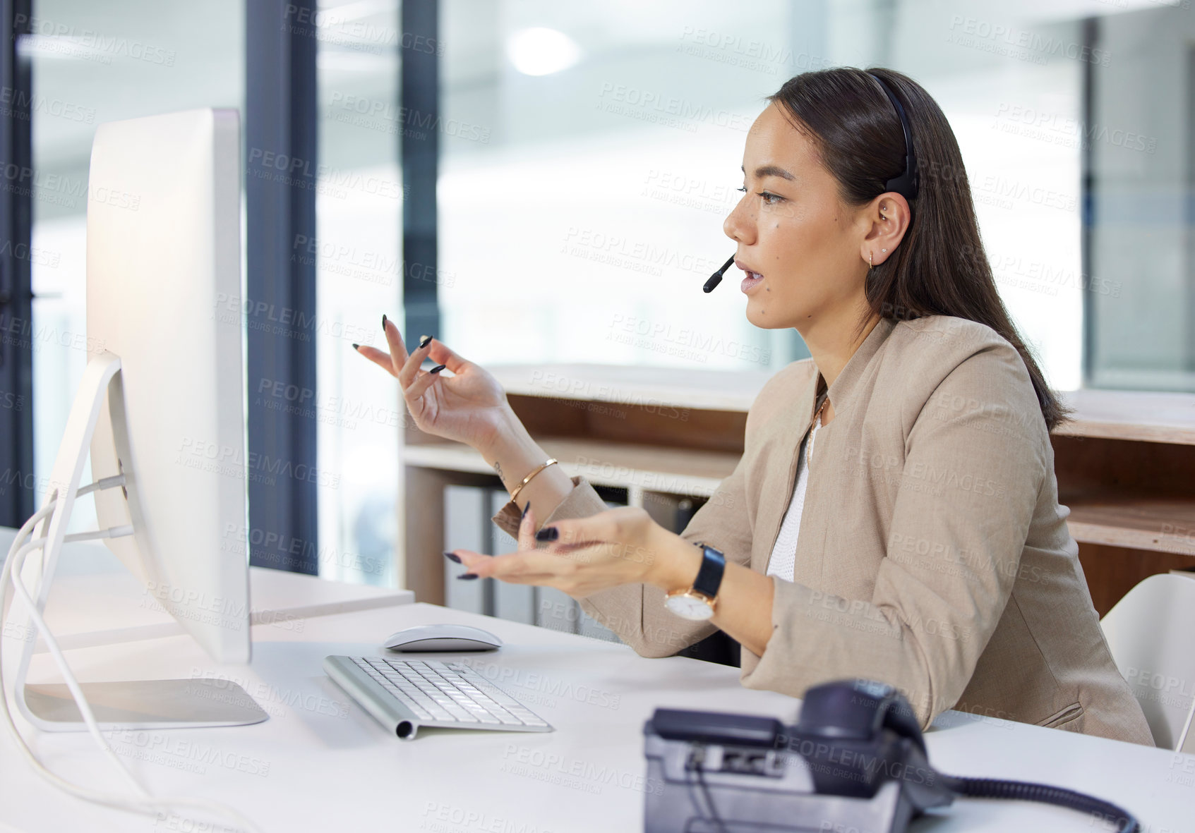 Buy stock photo Shot of a young woman using a headset and computer in a modern office