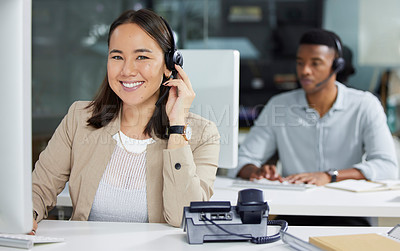 Buy stock photo Shot of a young woman using a headset and computer in a modern office