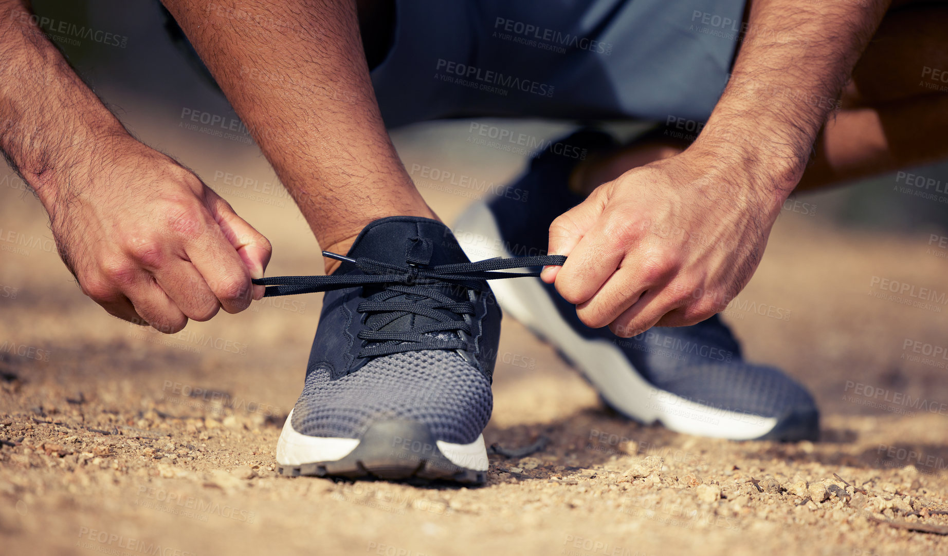 Buy stock photo Closeup shot of an unrecognisable man tying his shoelaces while exercising outdoors