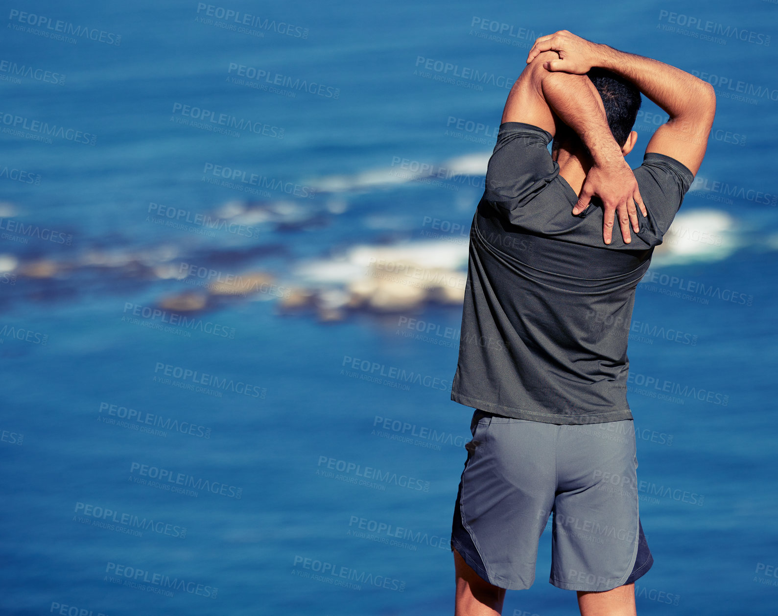 Buy stock photo Fitness, arms and man stretching by ocean before workout or morning training routine for race or wellness. Person, back view and outdoor with exercise for warm up for marathon, cardio and health.