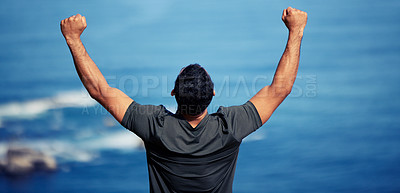 Buy stock photo Man, hiking and mountain celebration with hands as fist for exercise victory or outdoor cliff, back or workout. Male person, trekking and health goals at ocean or explore Australia, journey or travel