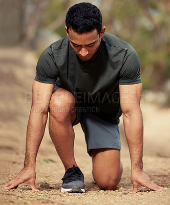 Buy stock photo Shot of a sporty young man in starting position while exercising outdoors