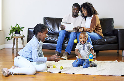 Buy stock photo Shot of a two young children sitting and playing in the living room while their parents use a digital tablet