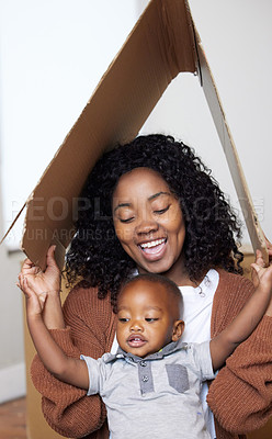 Buy stock photo Shot of an attractive young woman sitting with her son at home under a cardboard fort