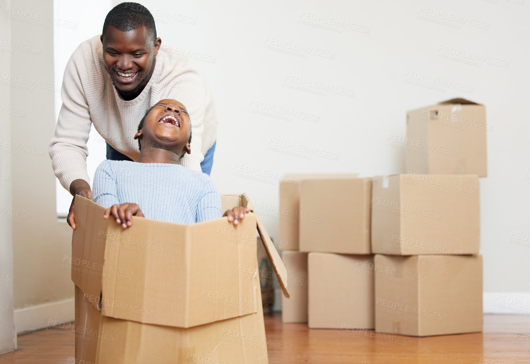 Buy stock photo Black man, child and playing with box in new home for moving, relocation or property together. African dad and kid with smile or laughing in happiness for playful bonding or investment in living room