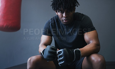 Buy stock photo Shot of an athletic man sitting next to a boxing bag