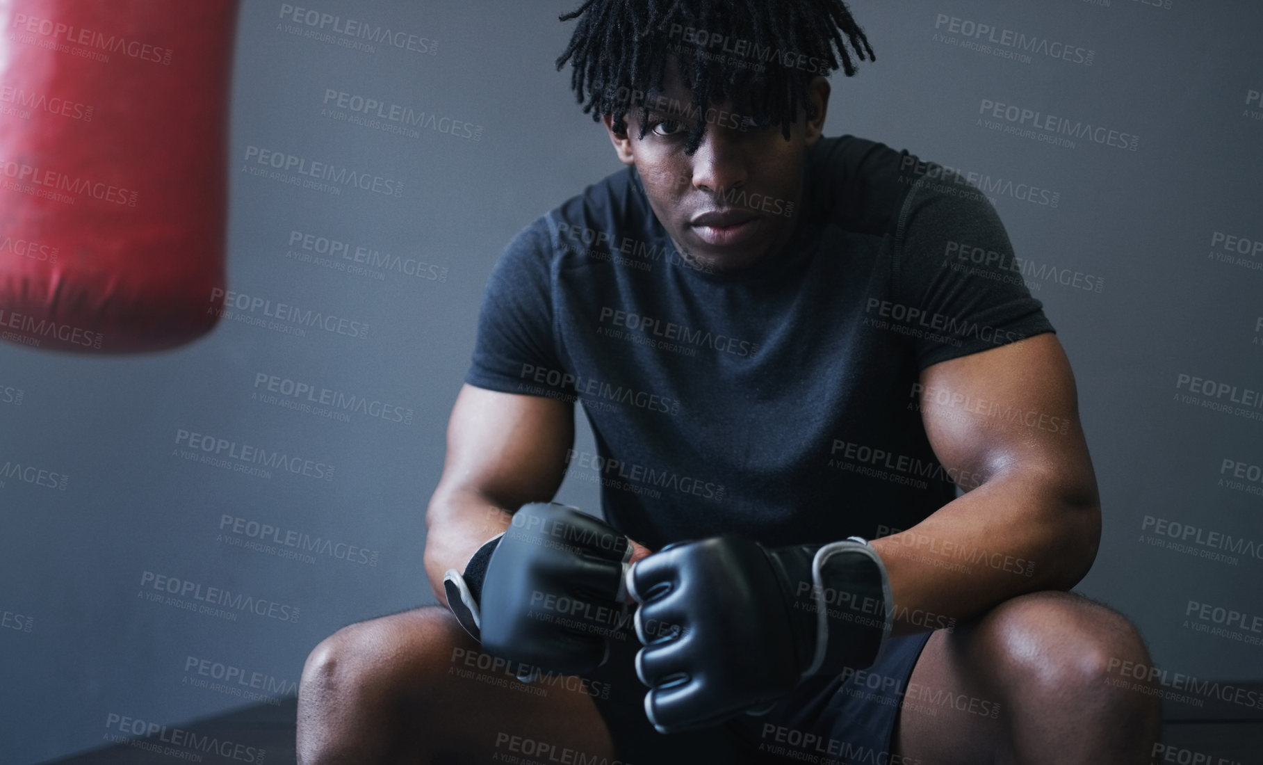 Buy stock photo Shot of an athletic man sitting next to a boxing bag