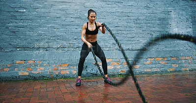 Buy stock photo Shot an athletic young woman doing battle rope waves