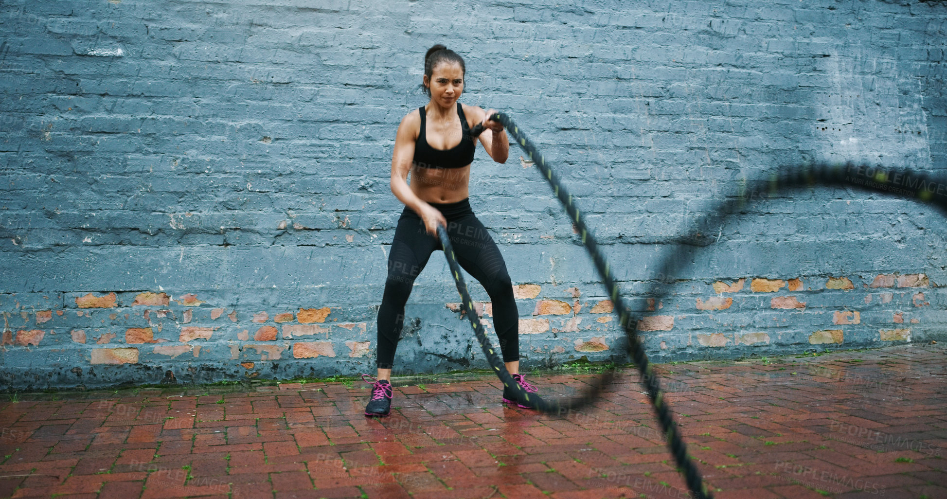 Buy stock photo Shot an athletic young woman doing battle rope waves