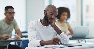Buy stock photo Black man, student desk and bored in university class with learning for college test at table. Book, school study and African male person thinking, writing and lecture notes for studying in classroom