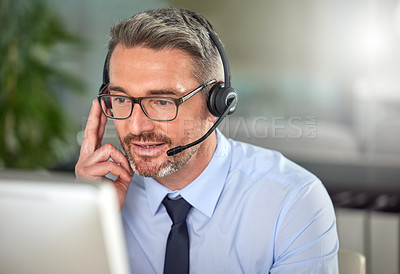 Buy stock photo Shot of a mature man using a headset and talking to clients while using his computer at work