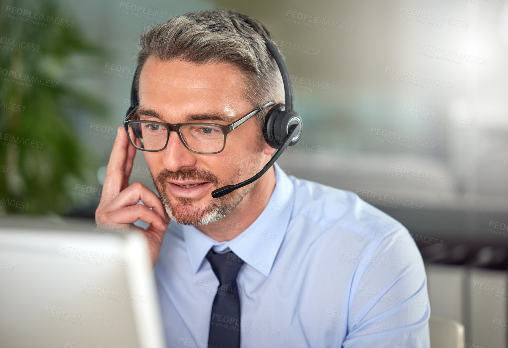 Buy stock photo Shot of a mature man using a headset and talking to clients while using his computer at work