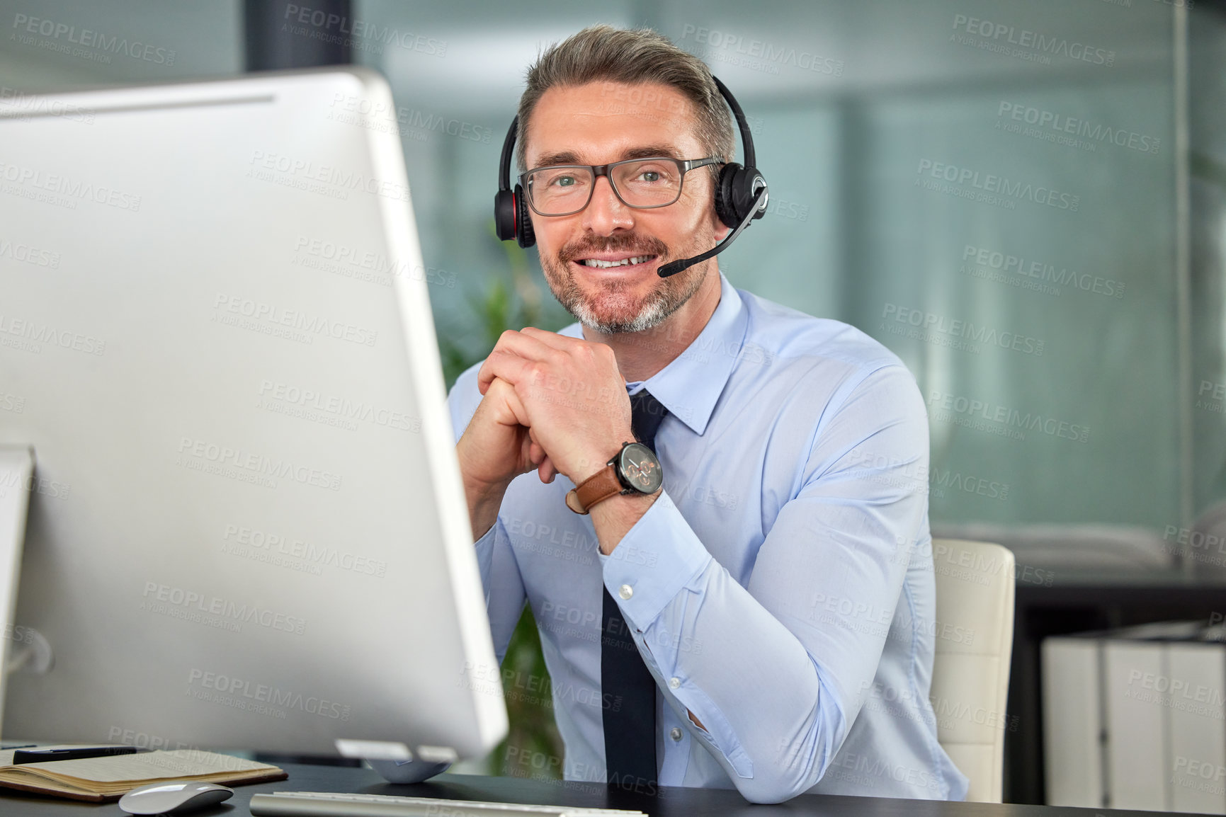 Buy stock photo Portrait of a mature man wearing a headset while using his computer at work