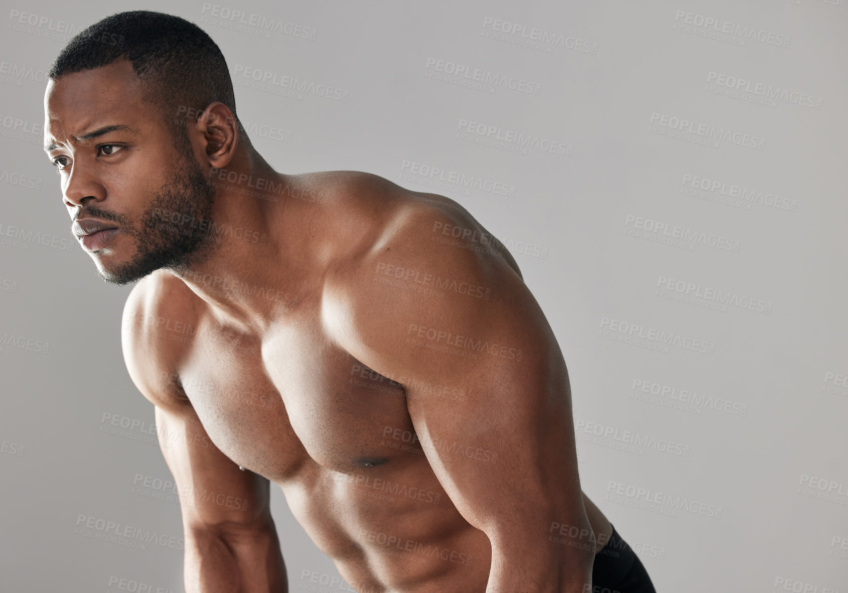 Buy stock photo Studio shot of a young muscular man posing against a grey background