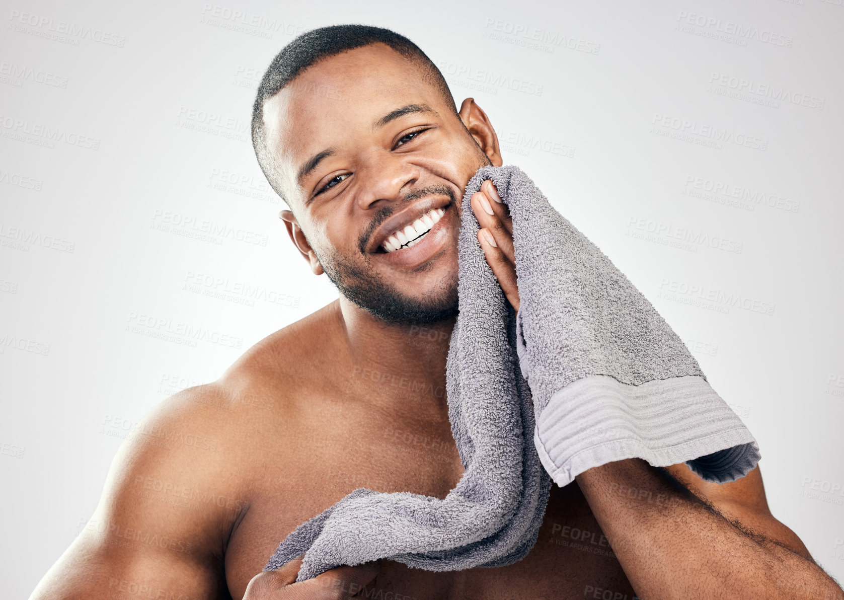 Buy stock photo Studio portrait of a handsome young man wiping his face with a towel against a white background