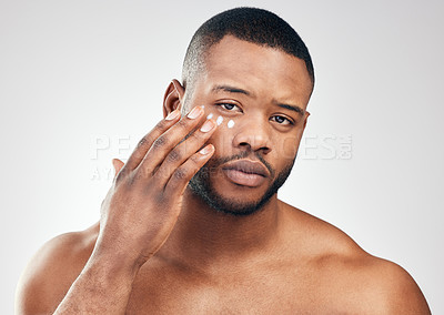 Buy stock photo Studio portrait of a handsome young man applying moisturiser to his face against a white background