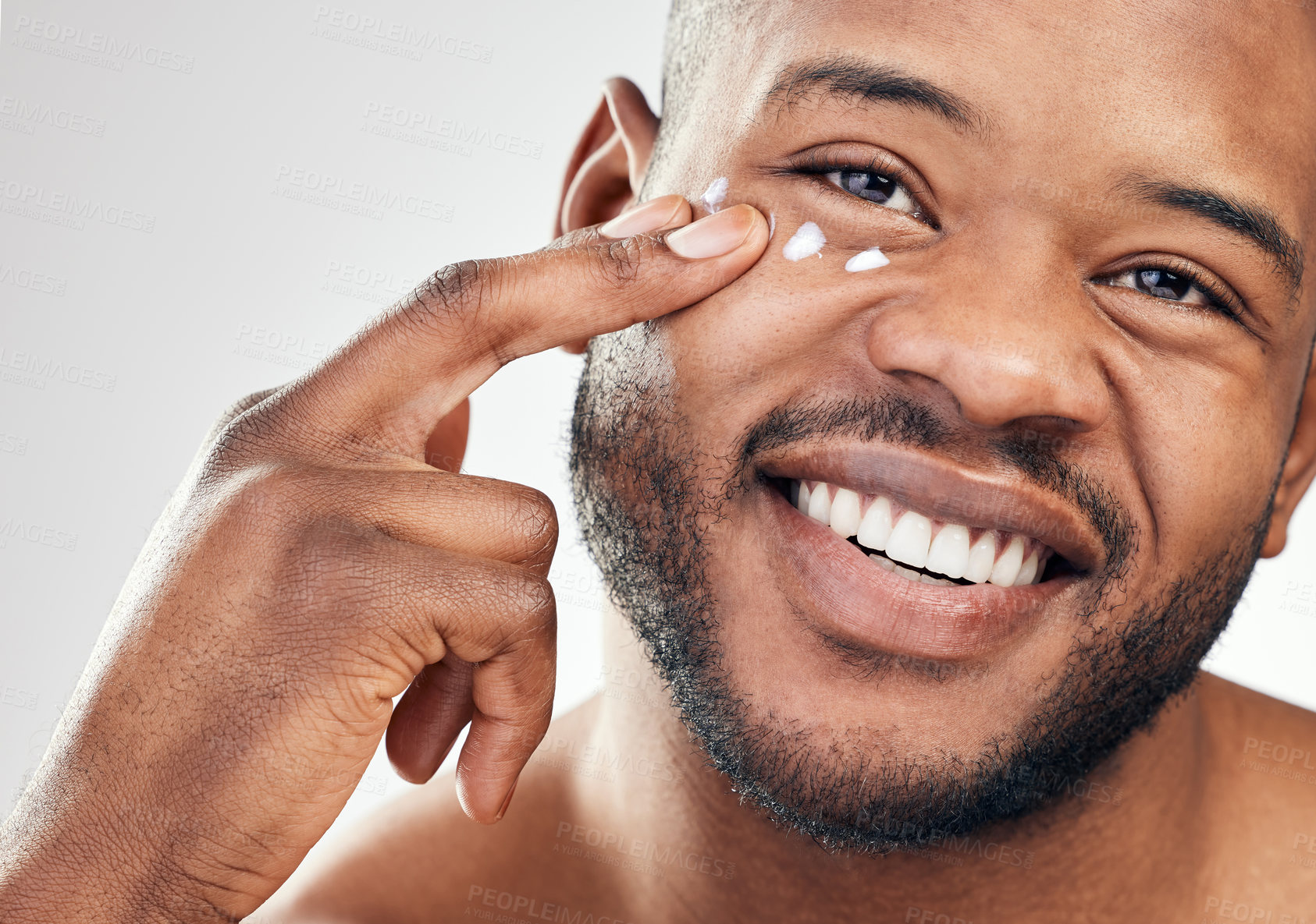 Buy stock photo Studio shot of a handsome young man applying moisturiser to his face against a white background