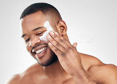 Buy stock photo Studio shot of a handsome young man applying moisturiser to his face against a white background