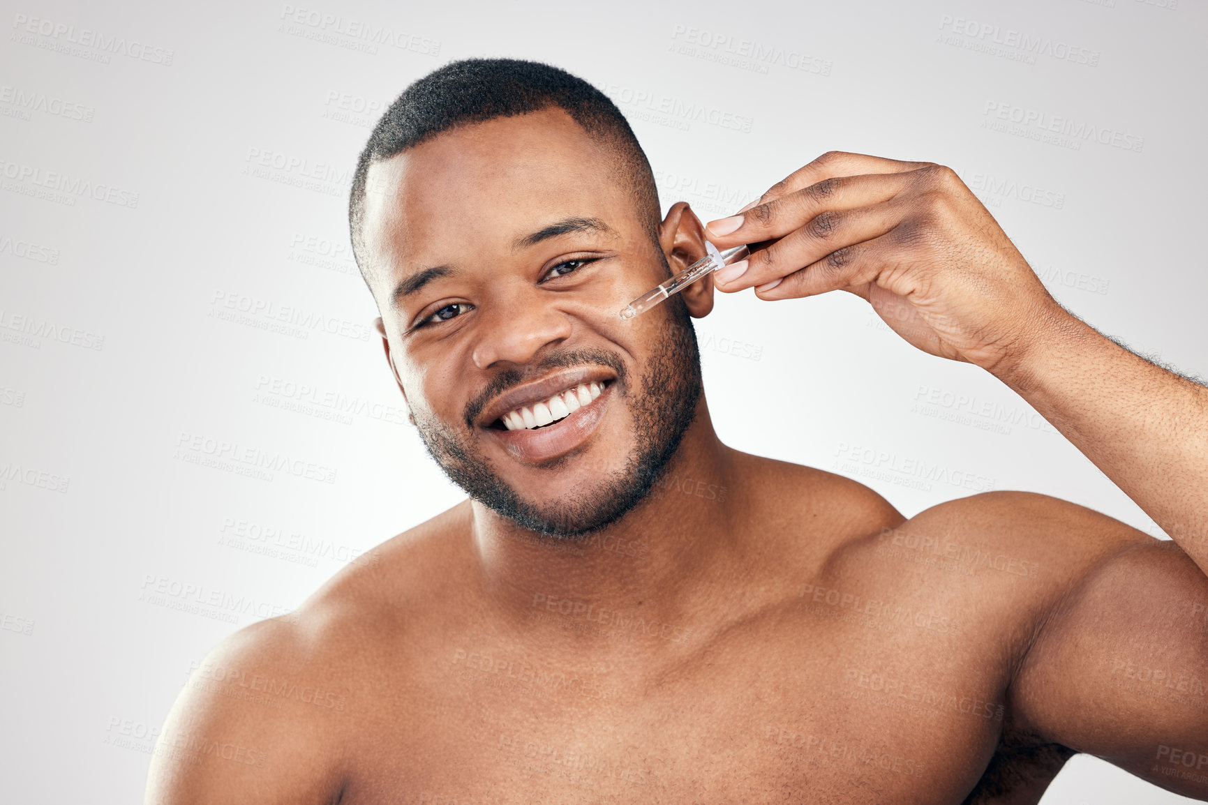 Buy stock photo Studio portrait of a handsome young man applying serum to his face with a dropper against a white background
